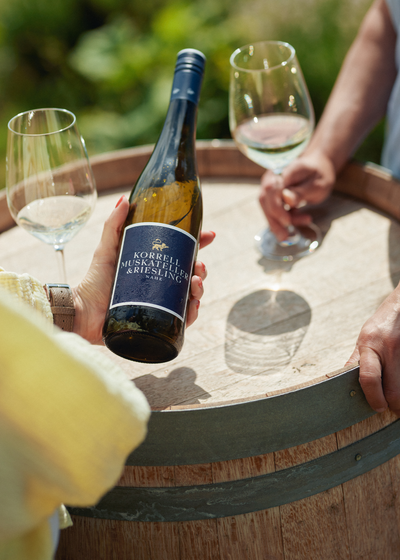 Muskateller & Riesling Flasche auf Fass in der Hand